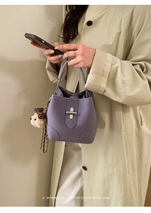 Detail der lila Beuteltasche mit silbernem Drehverschluss und Plüschbär-Anhänger