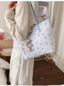 Quilted white tote bag with cute blue bear prints and plush charm shown on a model