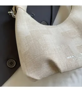 Close-up of beige knitted texture and brand logo detail on minimalist dumpling bag