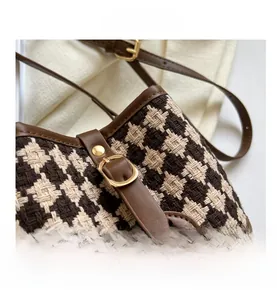 Detailed close-up of retro houndstooth bucket bag with leather trim and gold metal buckle