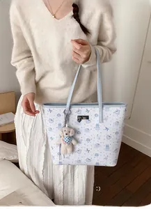 Close-up of quilted tote bag featuring cute cartoon bear prints and plush teddy pendant