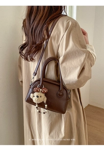 Detail of dark brown lychee leather bag with cute plush bear charm and retro vibe