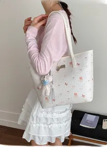 Close-up of white tote bag with pink cartoon patterns and bear plush charm