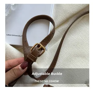 Detail of adjustable brown leather strap with golden metal buckle and stitching