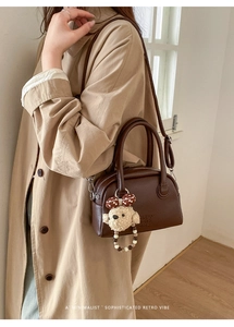 Detail of dark brown lychee textured bowling bag with cute plush bear charm accessory