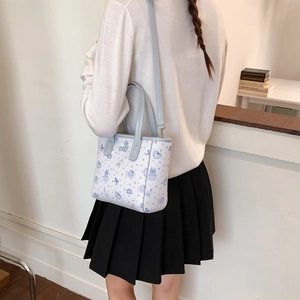 Vue détaillée du sac matelassé blanc avec bordure bleu clair et motifs de dessins