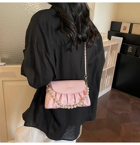 Detail of pink pleated handbag with pearl handle and metal chain strap for women