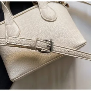 Macro detail of beige lychee grain leather handbag and adjustable silver metal buckle strap