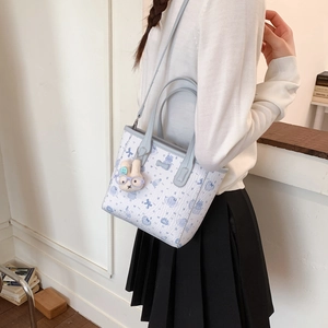 Détail d'un sac cabas vintage avec bordure bleue, imprimés cartoon et charm lapin en peluche