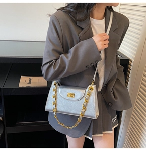 Détail d'un sac bandoulière argenté métallisé avec fermoir doré et bandoulière chaîne