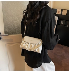 Detail of off-white pleated crossbody bag with pearl handle and golden brand logo