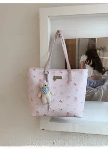 Detail of pink tote bag with embossed cartoon patterns and white teddy bear charm