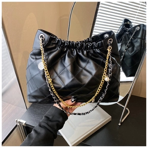 Close-up of black quilted shoulder bag featuring dual-tone chain and pearl charm