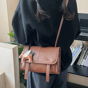 Detailed view of a brown vintage PU leather messenger bag with a Pegasus leather charm