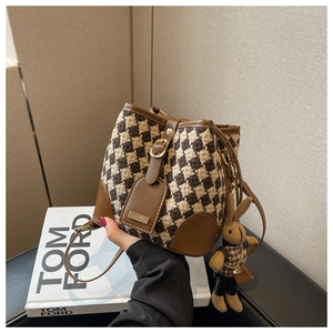 Detail of tweed bucket bag with leather trim and cute rabbit plush charm