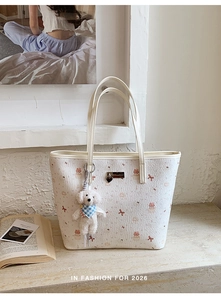 Detail of white tote bag with cartoon bear prints and cute plush dog pendant charm