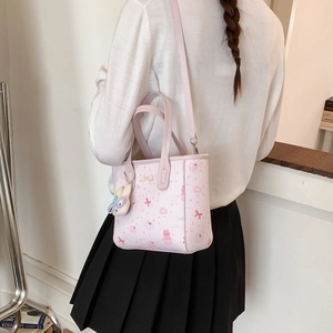 Détail d'un sac à bandoulière rose imprimé avec breloque lapin sur un mannequin