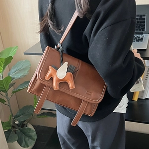 Brown vintage messenger bag with a decorative leather horse charm on the side