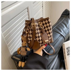 Detail of tweed bucket bag featuring houndstooth pattern and cute rabbit charm attachment