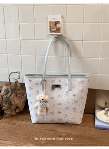 Detail of cute bear printed tote bag with plush dog charm and metal logo plaque