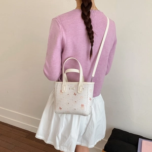 Vue arrière du mannequin portant un mini sac blanc à nœud rose et motifs animaux