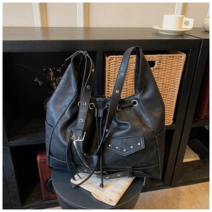 Detailed view of silver rivets and zipper accents on black leather punk bucket bag