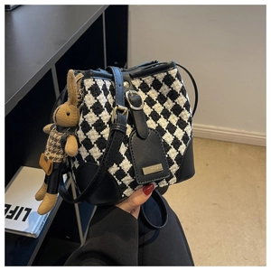 Detail of houndstooth bucket bag with black leather trim and cute rabbit pendant