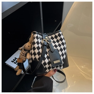 Detail of houndstooth bucket bag with leather trim and brown rabbit knit charm