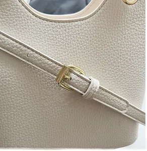 Close-up of adjustable strap with gold buckles on beige pebbled leather bucket bag