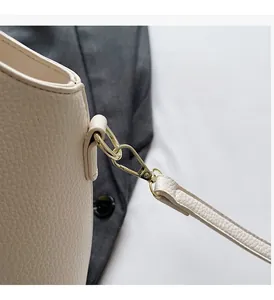 Close-up of golden swivel hook hardware on beige pebble grain leather bucket bag
