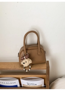 Dettaglio della borsa Boston in pelle marrone con un simpatico ciondolo a orsetto