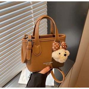 Brown lychee leather bucket bag detail with silver logo and cute plush puppy charm