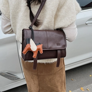 Detail of dark brown retro crossbody bag featuring a playful pegasus leather charm