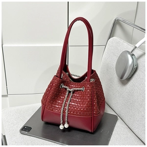 Detail einer roten gewebten Beuteltasche mit Metallzugband und weißen Perlenanhängern
