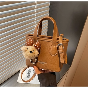 Brown lychee leather bucket bag detail with silver logo and cute plush bear charm