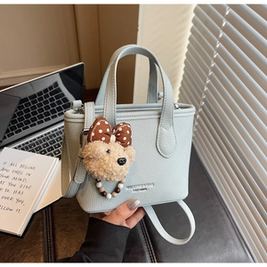 Detail of light blue pebble leather bucket bag with a cute teddy bear charm