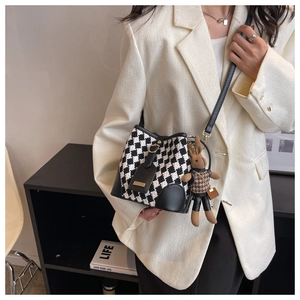 Detail view of checkered bucket bag with black leather trim and cute bunny charm accessory