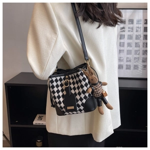Detail of checkered bucket bag featuring a cute plush bunny charm on a premium strap