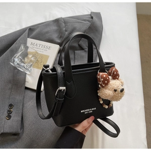 Detail of black pebbled leather bucket bag featuring cute bear charm and logo print
