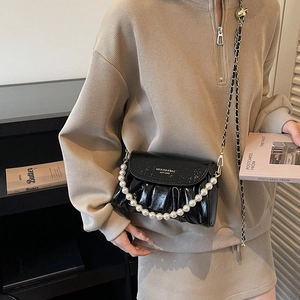 Black glossy ruched crossbody bag with large pearl handle and woven chain strap