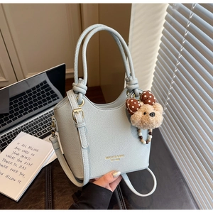 Detail of light blue lychee pattern leather bucket bag with gold lettering and bear charm