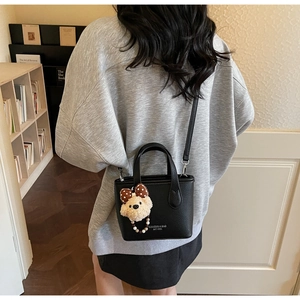 Detail of black lychee grain bucket bag with cute bear charm and shoulder strap
