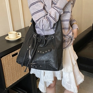 Retro punk black tote bag with silver studs and drawstring closure worn by a model