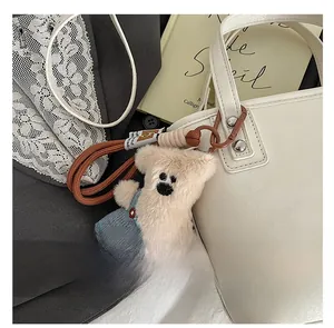 Détail d'un ours en peluche en salopette denim attaché à un sac fourre-tout sur un livre