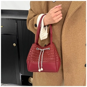 Detail der burgunderroten Beuteltasche mit Webstruktur und Kette mit Perlenzug