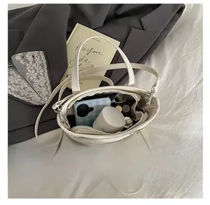 Intérieur spacieux d'un sac seau en cuir PU crème contenant maquillage et portable
