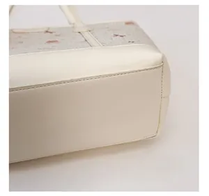 Detailed view of the structured base of the cream tote bag with contrast stitching