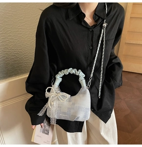 Detail of light blue checkered dumpling bag with pearl lace bow and metal chain strap