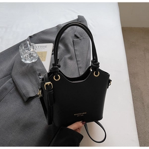 Close-up of black bucket bag featuring lychee texture leather and gold metal hardware