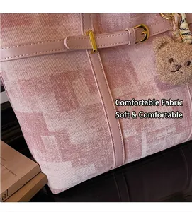Primer plano de bolso tote tejido rosa con colgante de osito y hebillas de metal dorado